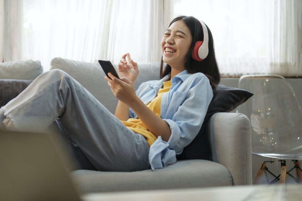 Young woman listening to music using smartphone at home.